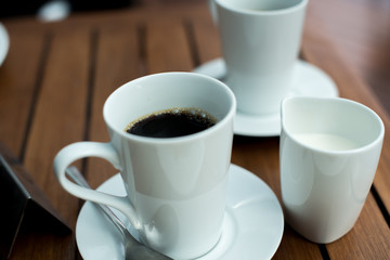 A cup of black coffee and mug of milk