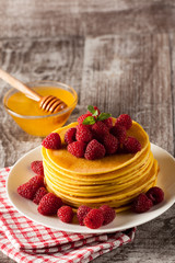 Fresh made delicious pancakes with berries, blackberries, raspberries, banana, honey and maple syrup. Healthy morning breakfast concept.