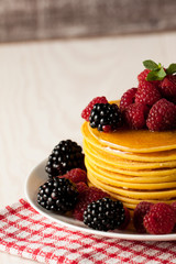 Fresh made delicious pancakes with berries, blackberries, raspberries, banana, honey and maple syrup. Healthy morning breakfast concept.