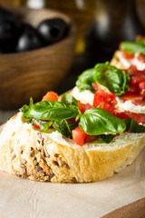Tomato and cheese fresh made bruschetta. Italian tapas, antipasti with vegetables, herbs and oil on grilled ciabatta and baguette bread.