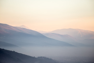 A valley filled by mist at sunset, with emerging trees and towns