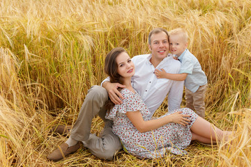 Cheerful family sitting in a wheat on the field