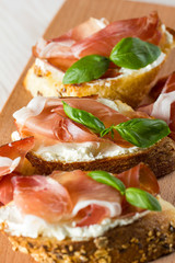 Italian tomato, prosciutto, jamon, ham and cheese bruschetta. Tapas, antipasti with chopped vegetables, herbs and oil on grilled ciabatta and baguette bread.