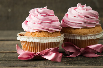 Closeup of cupcakes with vanilla, berries, pink and white cream, chocolate and sprinkles on wooden background. Selective focus. Sweet dessert tasty food concept muffin.