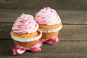Closeup of cupcakes with vanilla, berries, pink and white cream, chocolate and sprinkles on wooden background. Selective focus. Sweet dessert tasty food concept muffin.