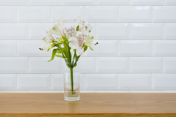 bunch flower in a vase on wooden table with white wall texture background.