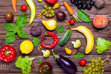 Healthy eating, diet, detox background. Assortment of bright organic fresh fruits and vegetables on the dark wooden table. Vegan, vegetarian, raw food. Top view, selective focus.