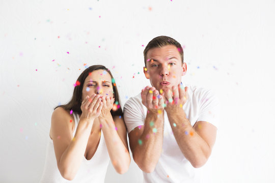 Young Man And Woman Blowing Confetti Decorations