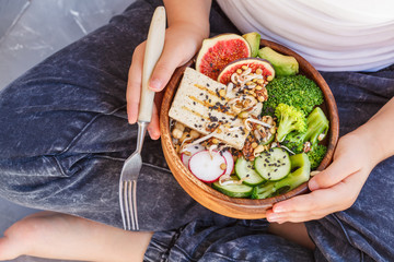 buddha bowl with tofu, broccoli and vegetables in the hands of a child