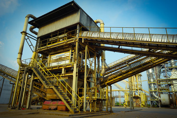 Particle board factory view of conveyor, lighting pole, building, logs storage