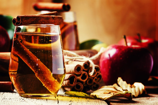 Apple juice with cinnamon, vintage wooden background, selective focus