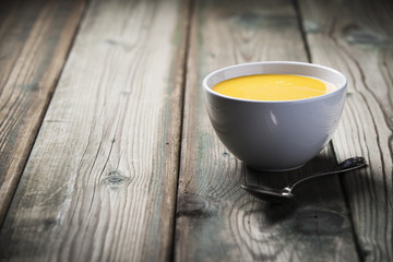 Vegetable cream soup in bowl over old wooden background