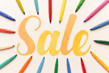 Orange painted lettering SALE on white background between markers