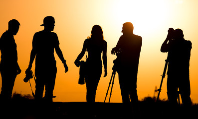 Silhouettes of people with cameras at sunset