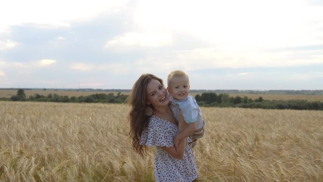 Mother with her son walking through a wheat field