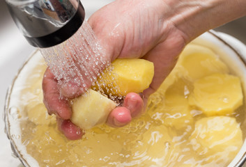 The cook washes the peeled potatoes in the water