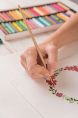 Young artist drawing pattern with watercolor paint and brush