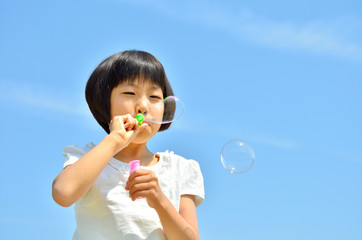 シャボン玉遊びをする女の子(青空)