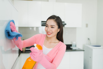 Beautiful asian young woman in protective gloves cleaning kitchen cabinet
