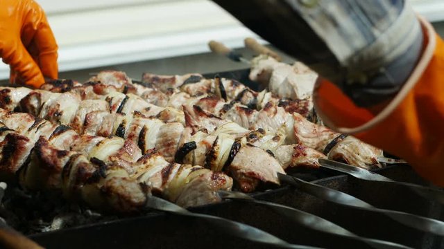 Hot Shish kebab on skewer. Cook roasts juicy kebab barbecue on the grill. Meat pieces being fried on a charcoal grill