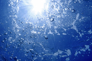 Under water air bubbles rising to water surface with sunlight in background, natural scene,...