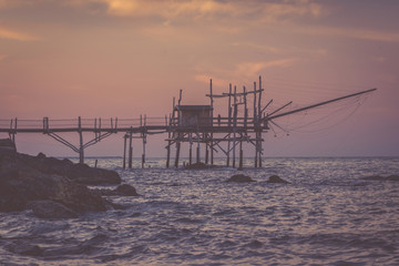 Lonely woman standing at trabocchi pier in nostalgic evening