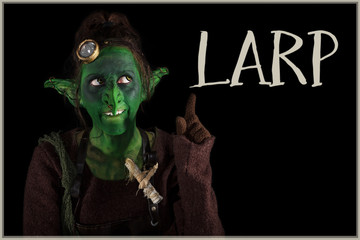 grüner Goblin zeigt freudig auf das Wort Larp