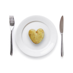 Plate with heart shaped potato and knife and fork