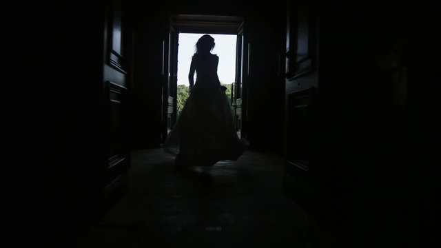 A girl in a white long dress is running around the old castle