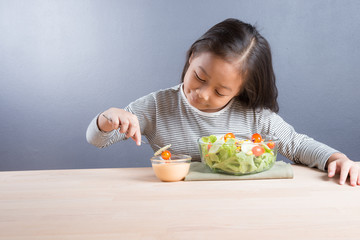 Portrait of healthy cute little asian girl happy to eat salad