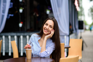 Happy and beautiful girl talking on the phone and drinking coffee.