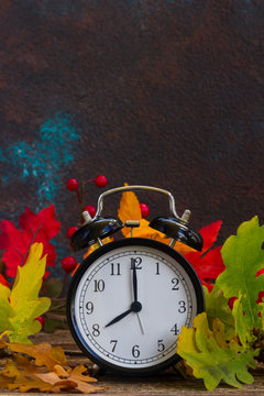Autumn time - fall leaves with alarm clock