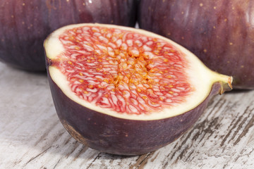 Fruits of whole and half fresh figs on wooden plank, close up.