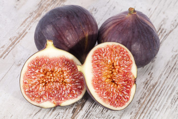 Fruits of whole and half fresh figs on wooden plank, close up.