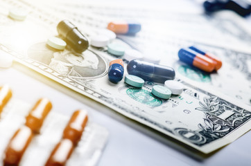 Pharmacy background. Pills on a banknote isolated on a white background. Different types of capsules on dollars banknote. Money and pharmaceutical industry.