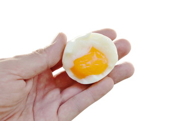 boiled egg half cut with creamy yolk holding on hand in white background