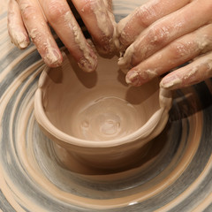 Woman in process of making clay bowl on pottery wheel