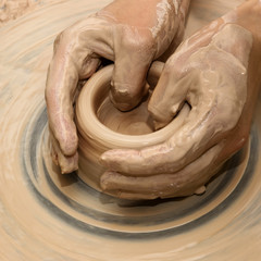 Hands in clay at process of making ceramic on pottery wheel
