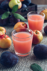 Fresh plum juice . Juice in a glass garnished with fresh plums and tiny apples on a linen napkin