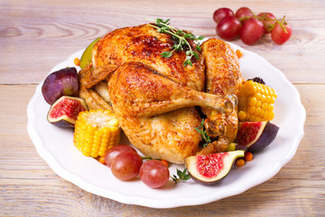 Whole chicken with fruits, vegetables and berries: figs, corn on cob, grape, plums and blackberry, horizontal