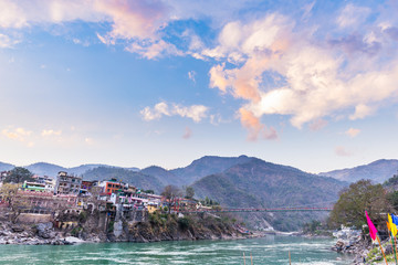 Fototapeta premium Dusk time at Rishikesh, holy town and travel destination in India. Colorful sky and clouds reflecting over the Ganges River.
