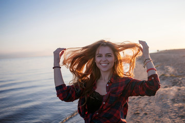 Charming young woman walks on the beach. Youth style, laughs and enjoys life