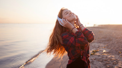 Young woman enjoying the music, wonderful evening on the beach
