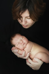 mom and newborn baby on dark background close-up