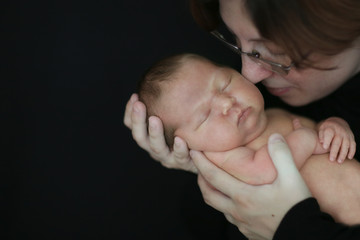 brunette mom and newborn baby on  dark background