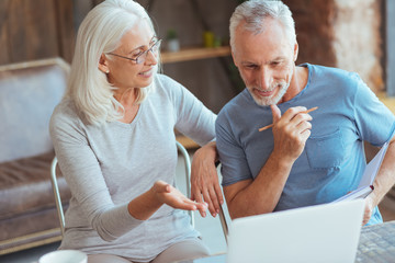 Cheerful aged couple using laptop
