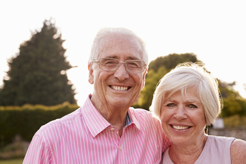 Senior couple in garden smiling to camera, close up