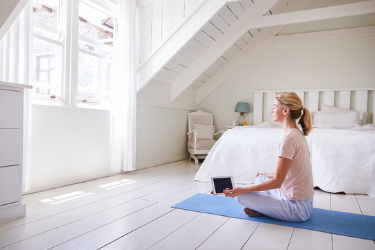 Woman With Digital Tablet Using Meditation App In Bedroom