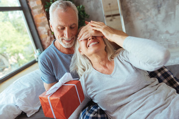 Loving aged man giving present to his nice wife
