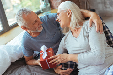 Positive aged loving couple holding a present